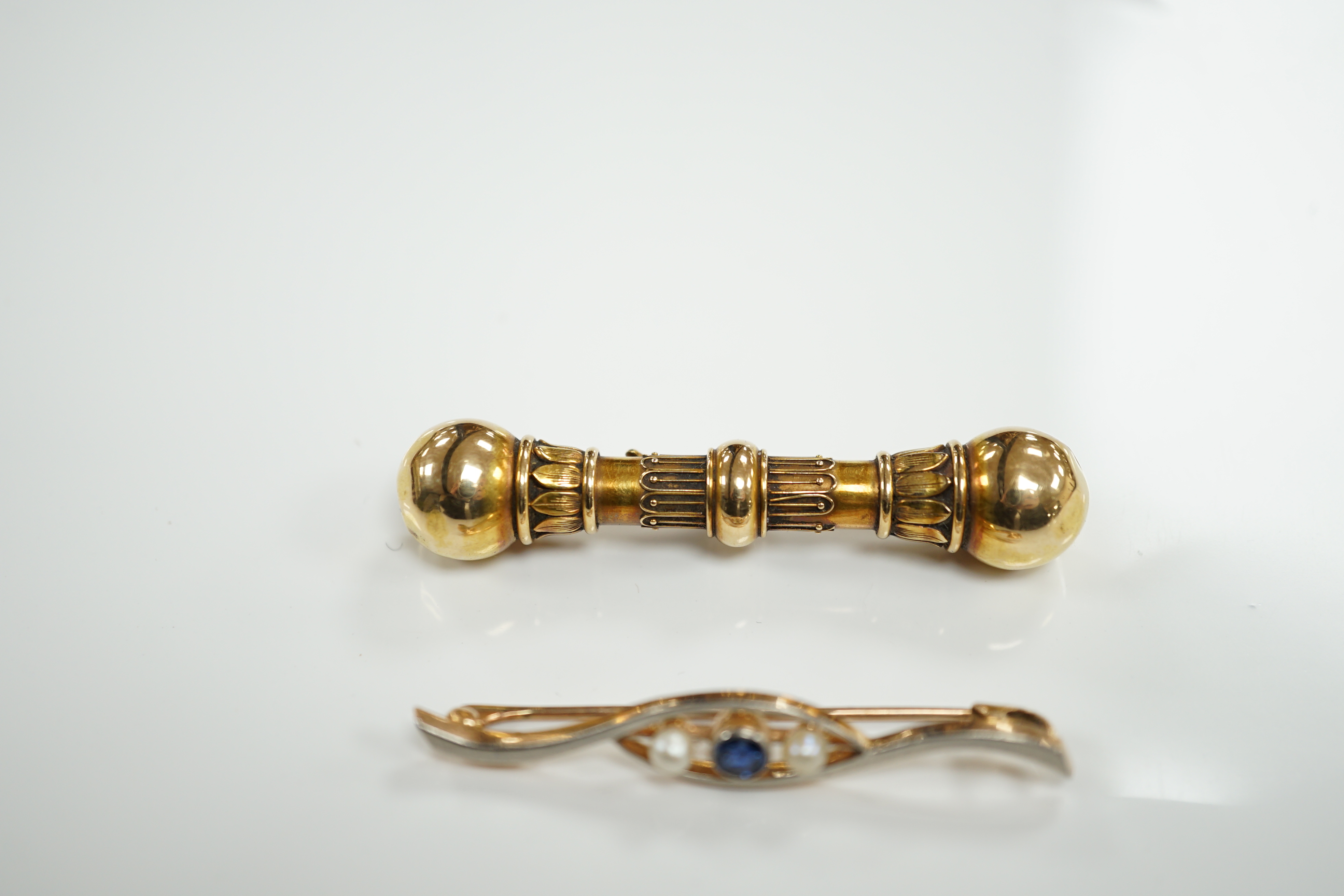 A Victorian yellow metal 'dumbbell' bar brooch, with engraved inscription dated 1862, 56mm and a later 15ct, sapphire and seed pearl set three stone crossover bar brooch.